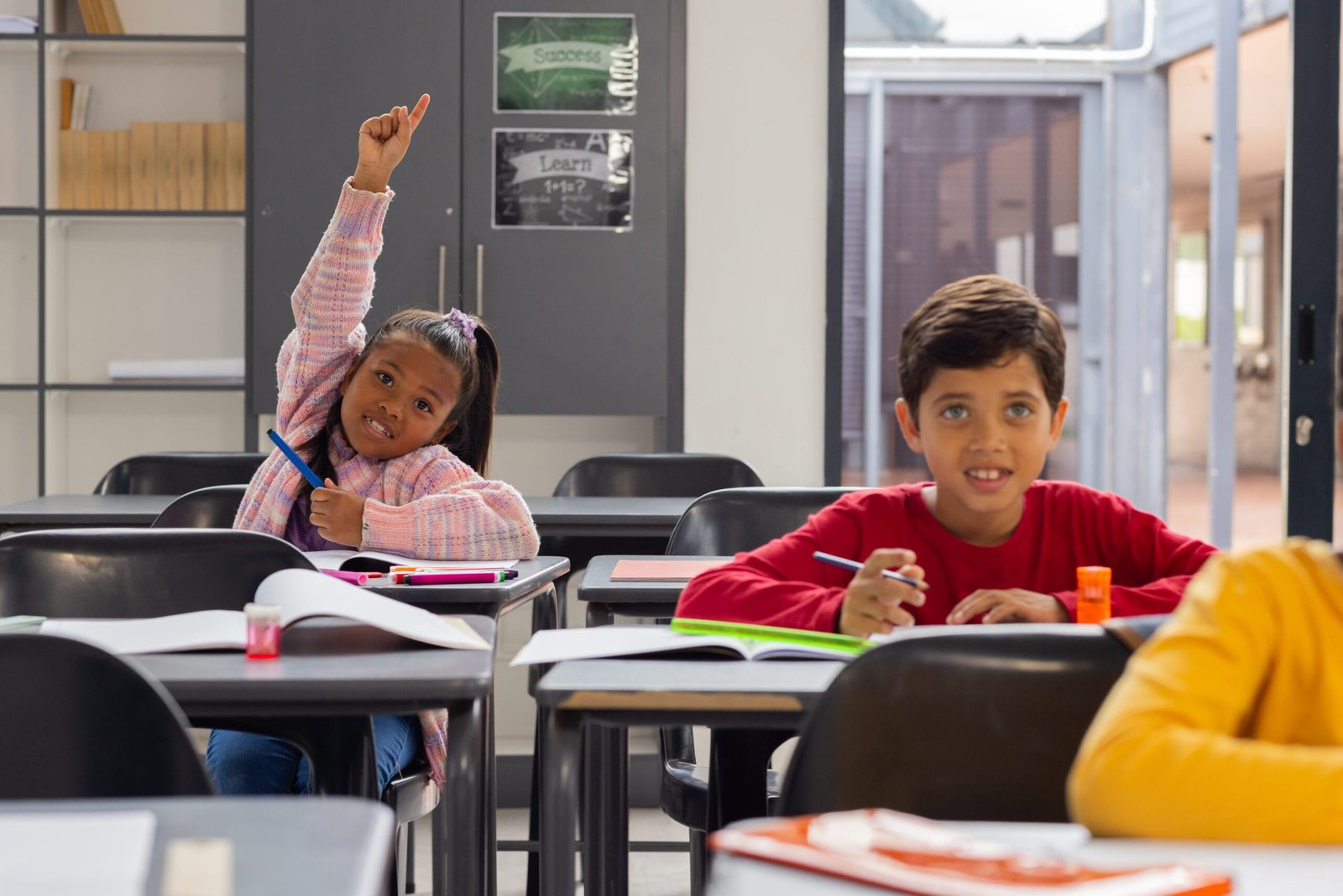 biracial-girl-in-a-pink-plaid-shirt-raises-her-hand